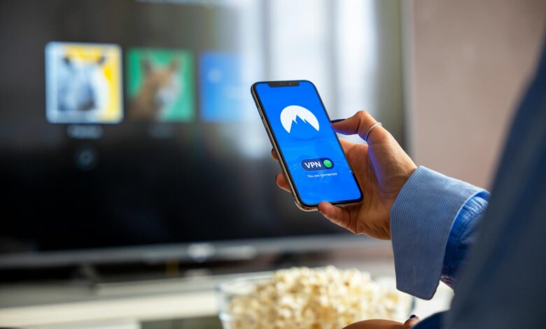 Hand holding streaming device remote control with Netflix interface on television screen