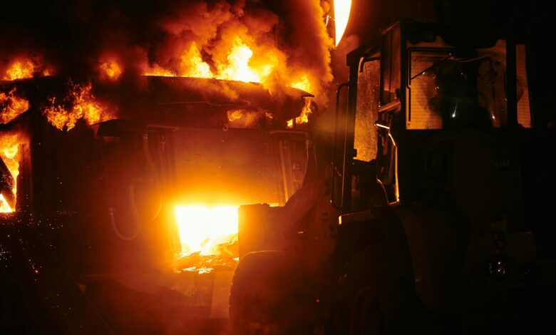 Large industrial fire with flames and smoke against dark sky
