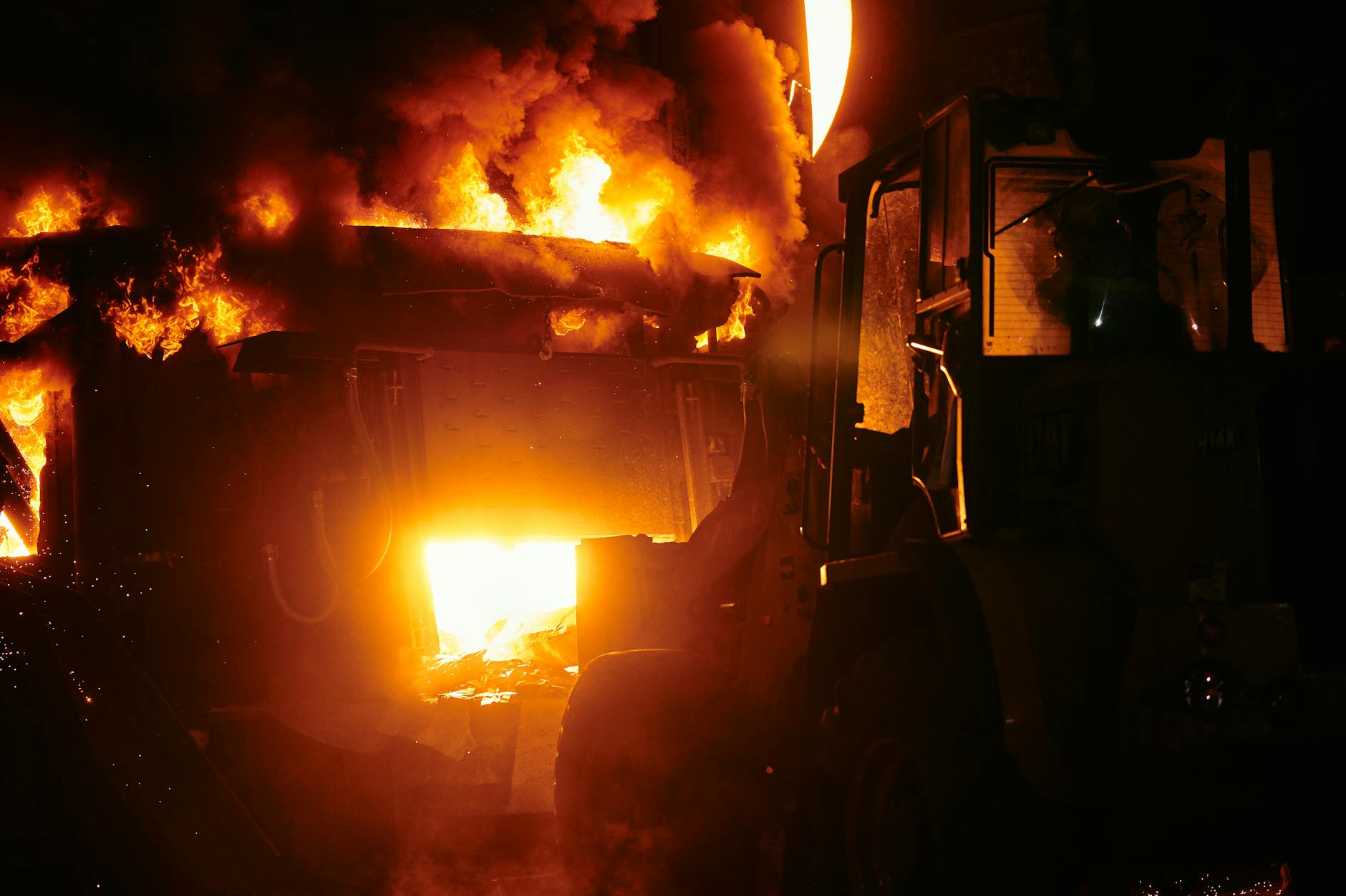 Large industrial fire with flames and smoke against dark sky