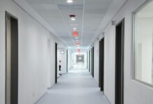 Empty hospital corridor with medical equipment and patient rooms