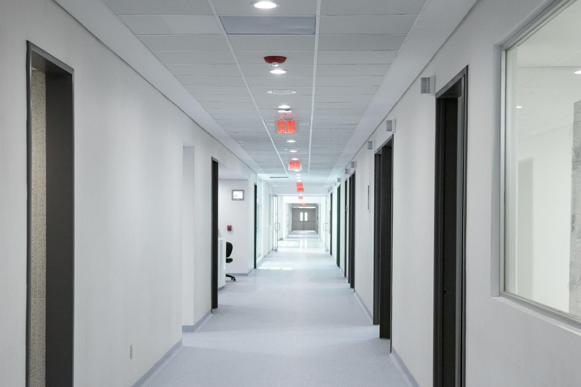 Empty hospital hallway with medical equipment and patient rooms