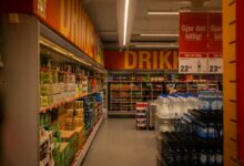 Wide grocery store aisle stocked with packaged food products and fresh produce