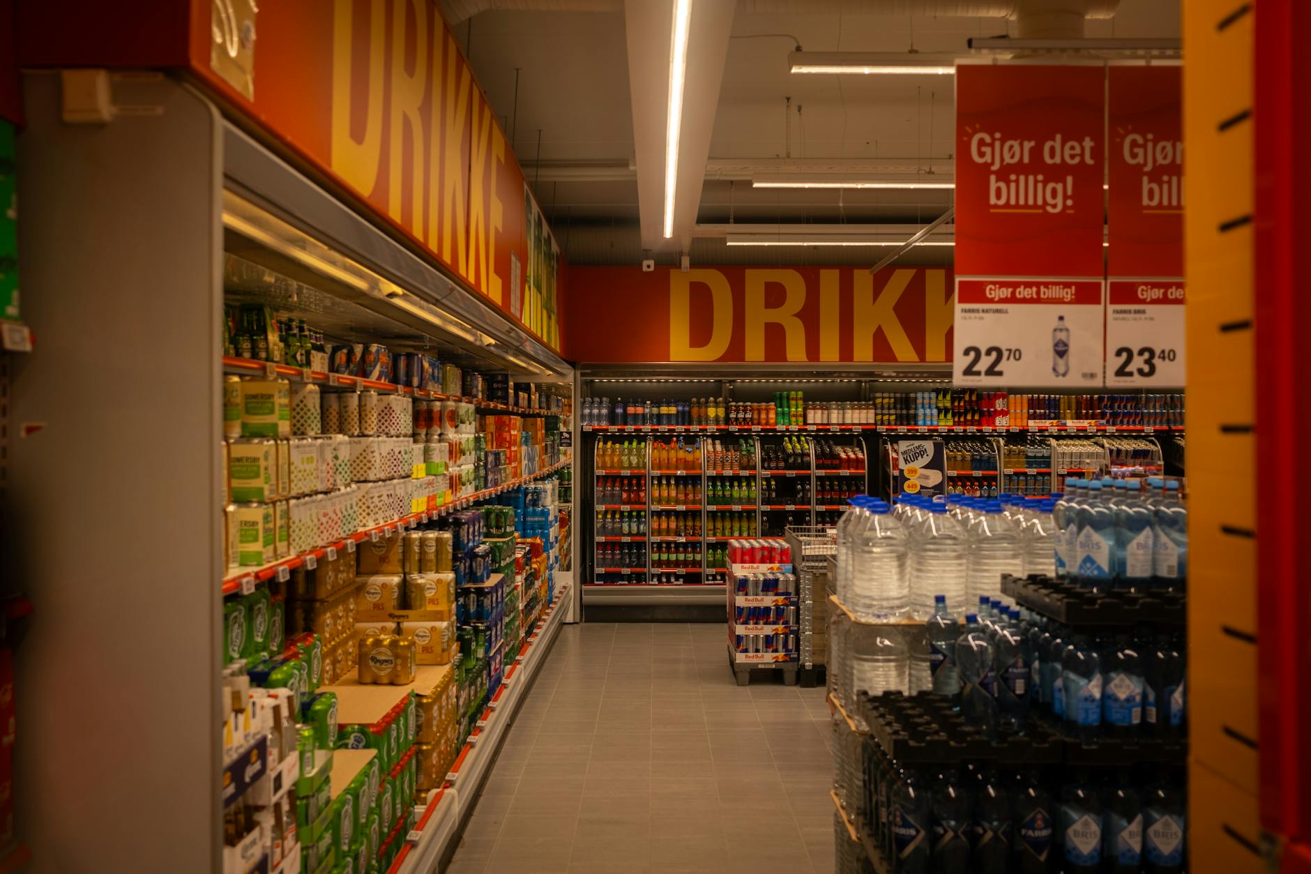 Wide grocery store aisle stocked with packaged food products and fresh produce