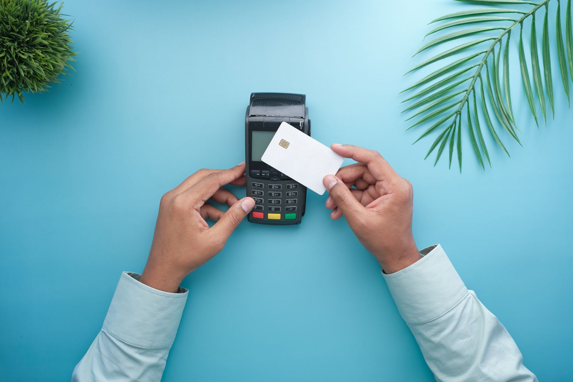 Person tapping a credit card on a payment terminal at a retail counter