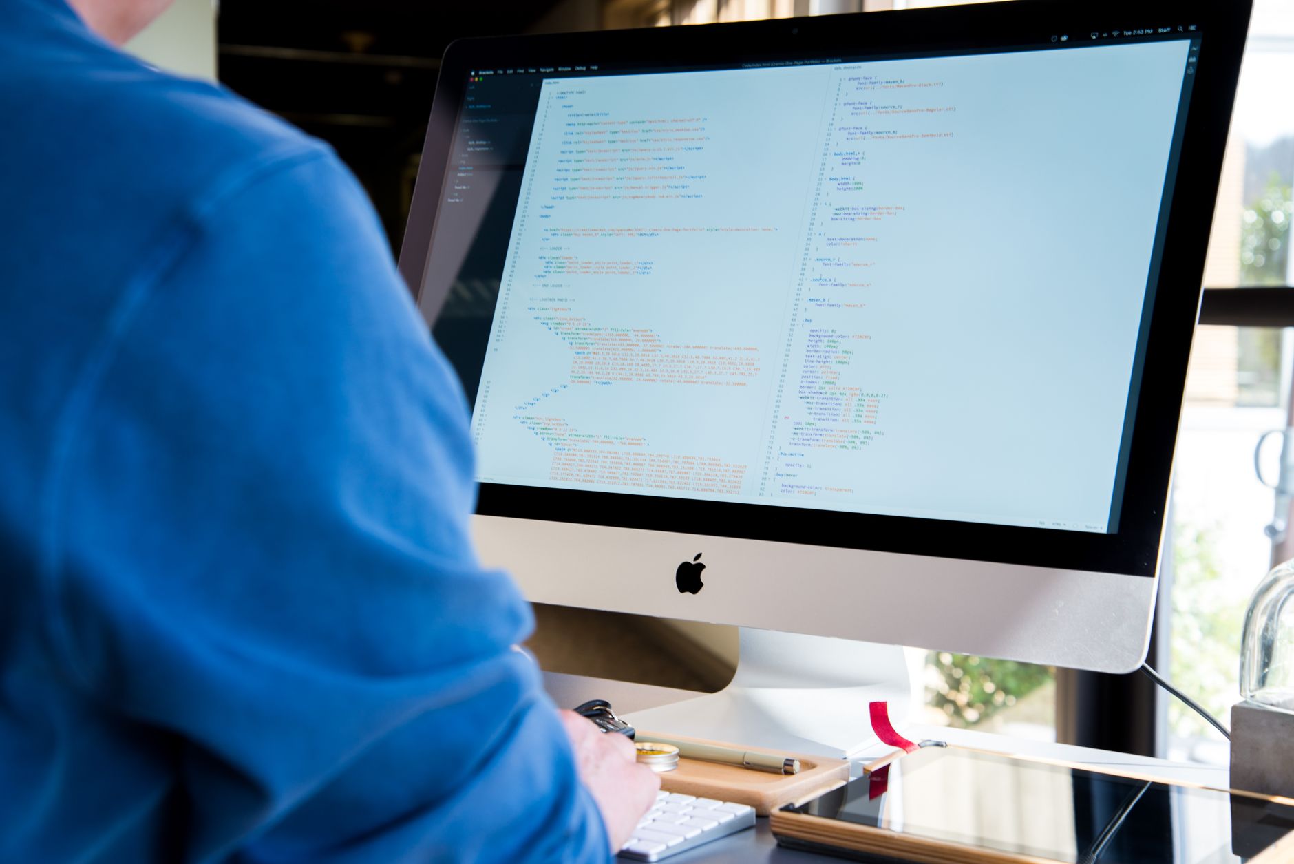 Software developer writing code on multiple monitors in a modern workspace