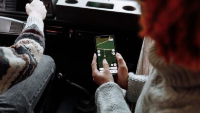 Person using a rideshare app on a smartphone while waiting on a city street