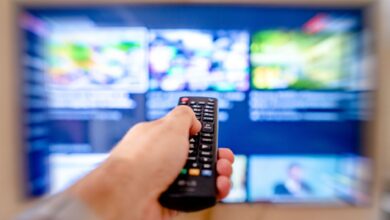 Person using a TV remote to browse a streaming service on a large screen
