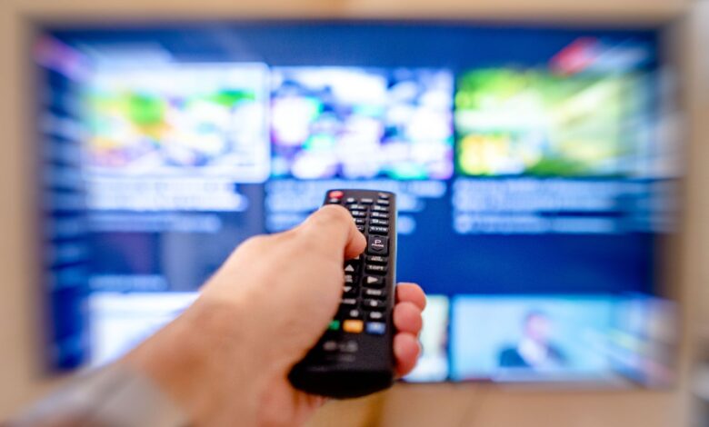 Person using a TV remote to browse a streaming service on a large screen