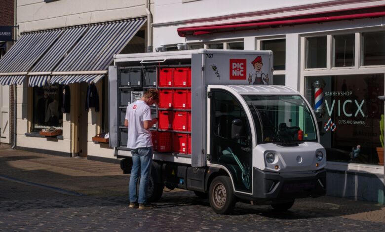 An electric delivery van parked outside a distribution center