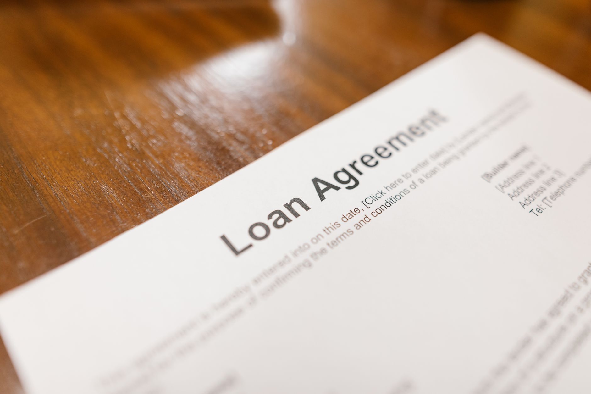 Person signing loan documents at a desk with financial paperwork