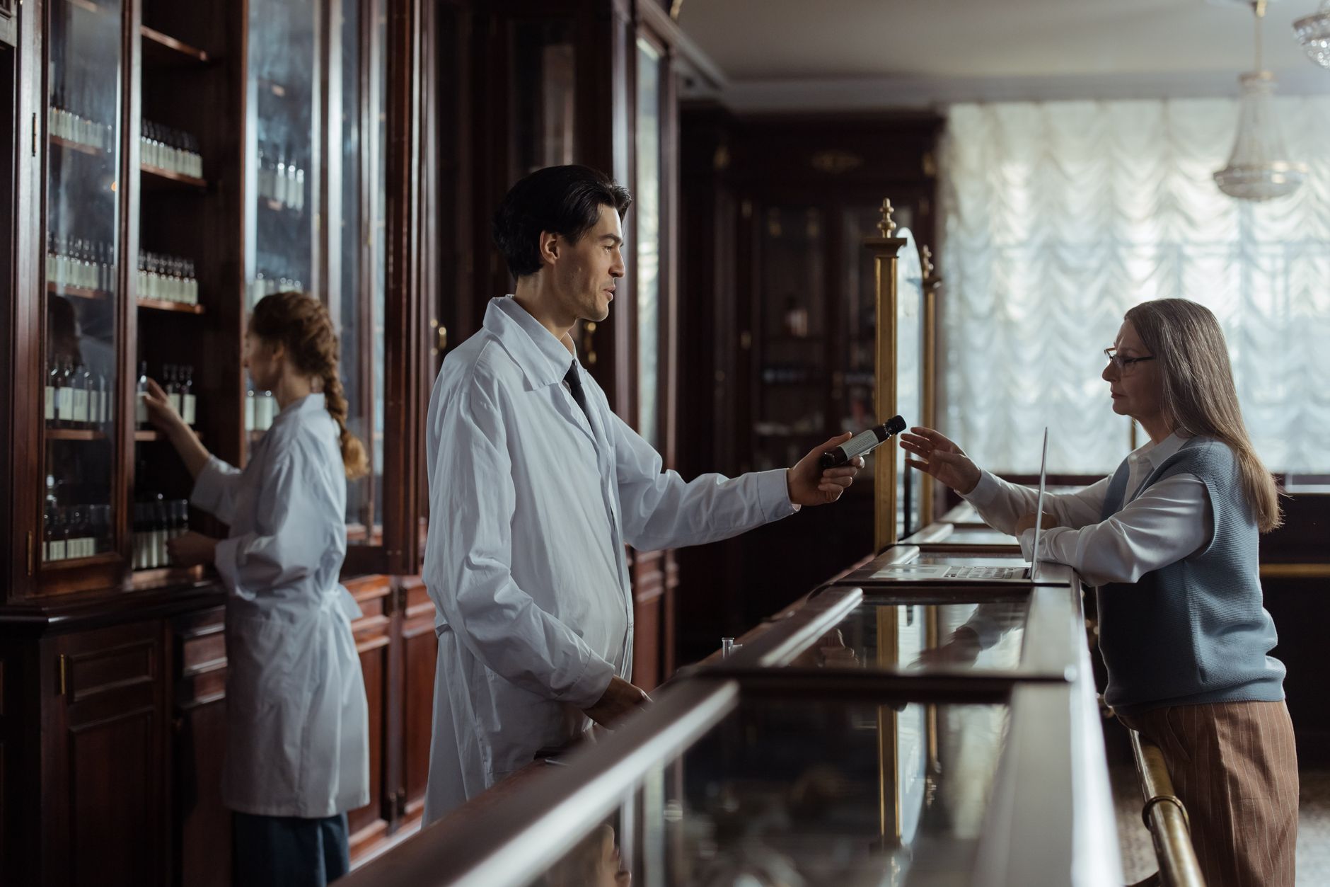 Pharmacist at a retail pharmacy counter dispensing prescription medication