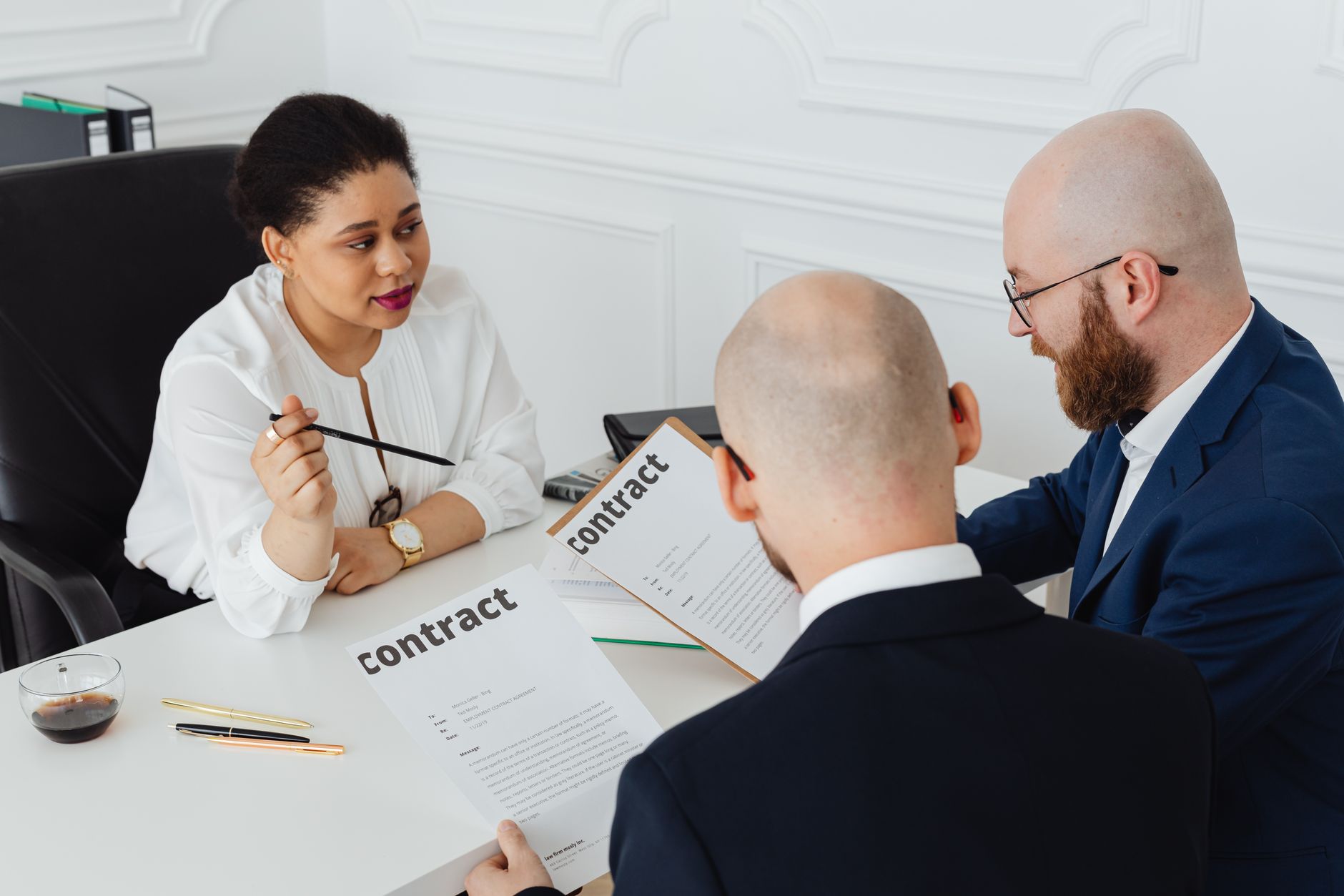 Two business professionals reviewing and signing a contract at a meeting table