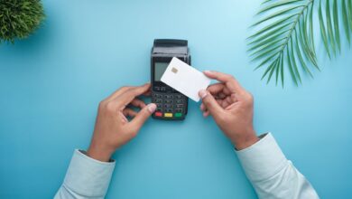 A customer tapping a credit card on a modern payment terminal at a small retail checkout counter
