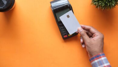A shopper tapping a card on a contactless payment terminal at a retail checkout counter