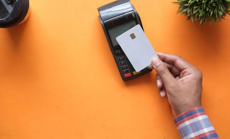 A customer tapping a debit card on a contactless payment terminal at a retail checkout counter