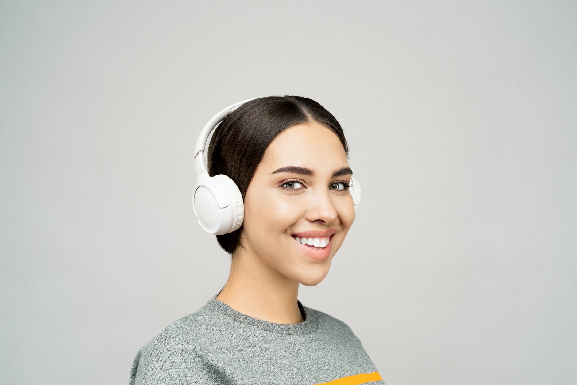 Woman wearing headphones listening to audio content on a smartphone