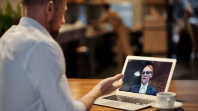 Team members participating in a video conference call on laptops in a modern office setting