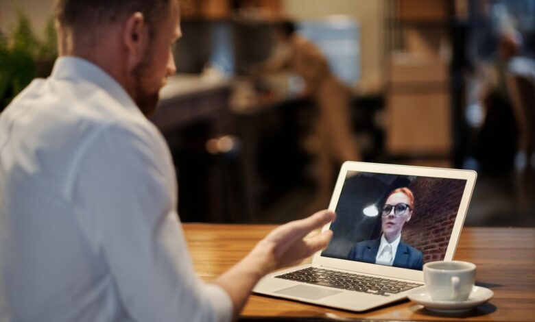 Team members participating in a video conference call on laptops in a modern office setting