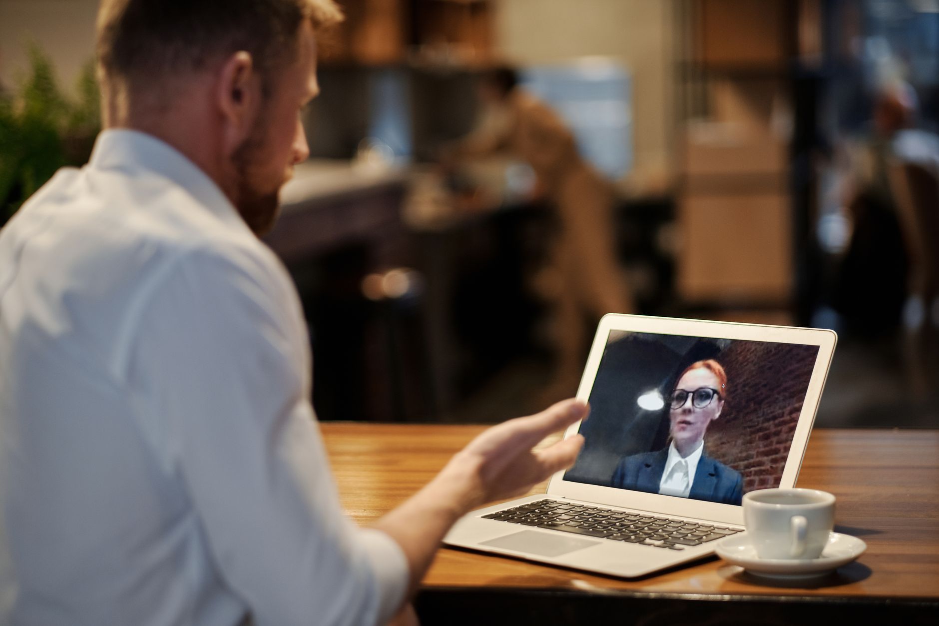 Team members participating in a video conference call on laptops in a modern office setting